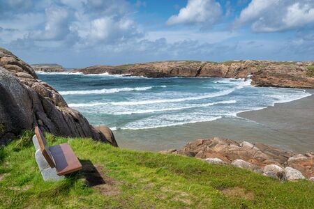Empty bench over looking a beach in Donegal Ireland with waves coming in from the ocean