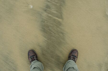 A look down on boots on a sand floorの写真素材
