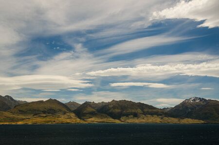 Mountains landscape with lake in front on blue cloudy skyの写真素材