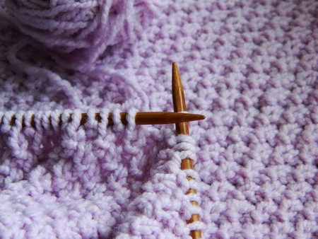 Knitted purple pattern with needles and skeinの写真素材