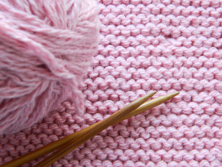 Knitted knitting with knitting needles. Pink color