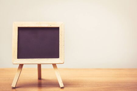 chalkboard with easel stand on wooden table in vintage toneの写真素材