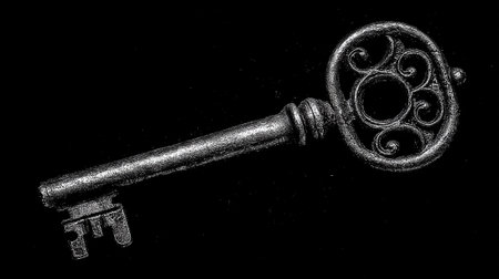 Old key on a black background. Conceptual image of security.の素材