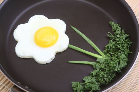 Flower shaped fried egg with parsley and spring onionsの写真素材