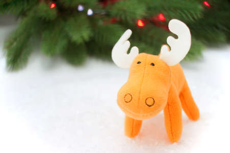 Toy scene with orange elk in artificial snow with pine on backgroundの写真素材