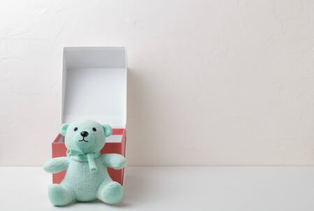 Turquoise soft toy teddy bear on a textured background next to a red gift boxの写真素材