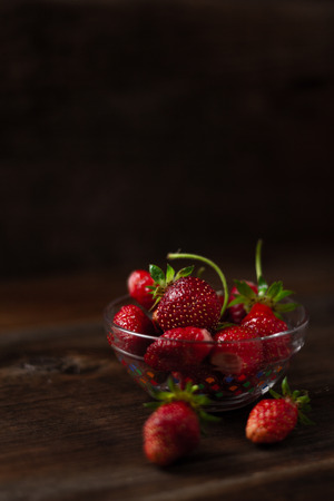 Strawberries in a cup on a wooden tableの写真素材