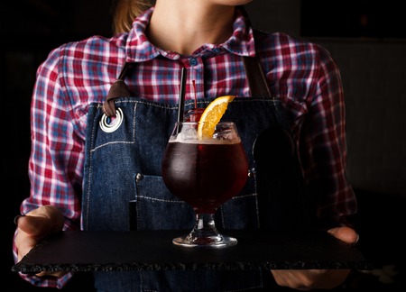 Girl waiter holds an alcoholic cocktail. checkered shirtの写真素材