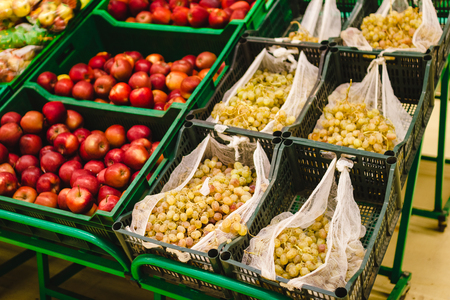 Bunch of red apples and green grapes on boxes in supermarket.の写真素材