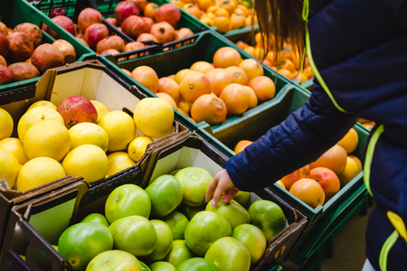 woman's hand choosing orange from the food counter at the supermarketの写真素材