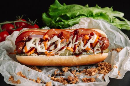 Hot dog with yellow mustard, lettuce and onions on craft paper, close upの写真素材