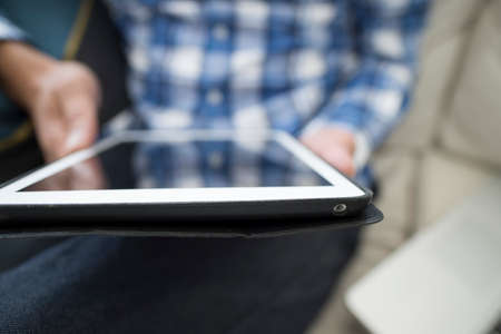 Closeup of the hands of men that use the tablet is at home on the couchの写真素材