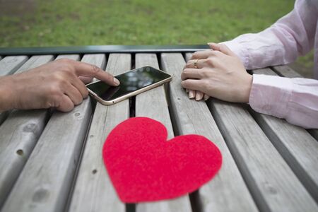 Man and Women who use the smart phone in the parkの写真素材