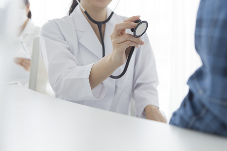 Young female doctor examine male patient with stethoscopeの写真素材
