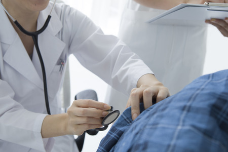 Medical doctor giving checkup with stethoscope to young girl over white backgroundの写真素材