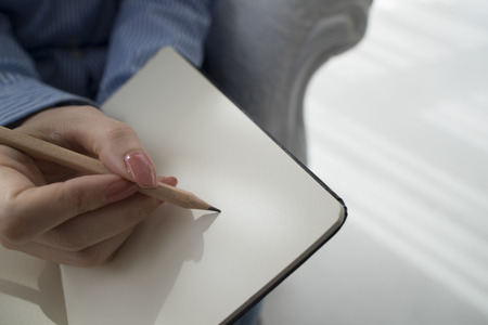 Humans hand holding pencil on isolated white background, top viewの写真素材