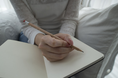 hand of young woman taking notes in notebook