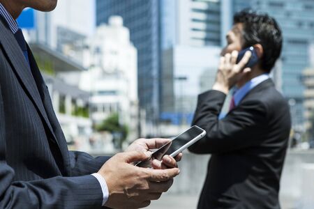 Happy businesspeople using mobile phones at office lobby - plenty of copyspace.の写真素材
