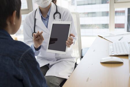 Woman doctor has described the boy using a tablet computerの写真素材