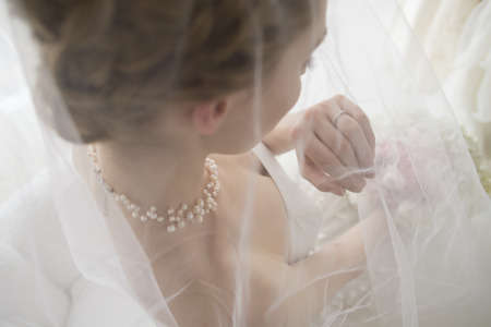 Beautiful bride is staring at the wedding ring that is attached to the handの写真素材