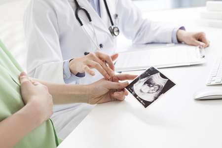 Female doctor show the echo photo to pregnant womanの写真素材