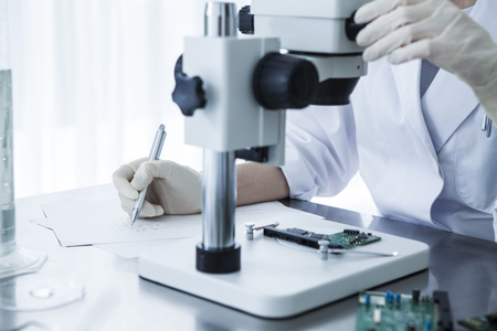 close-up of scientist hands with microscope, examining parts.の写真素材