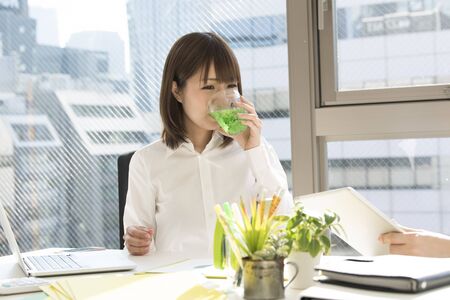 A woman with a white shirt drinks melon soda.の写真素材