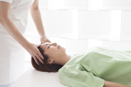 A lady lying on bed, receiving a massage.の写真素材