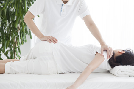 A woman lying on the bed and receiving rehabilitation.の写真素材