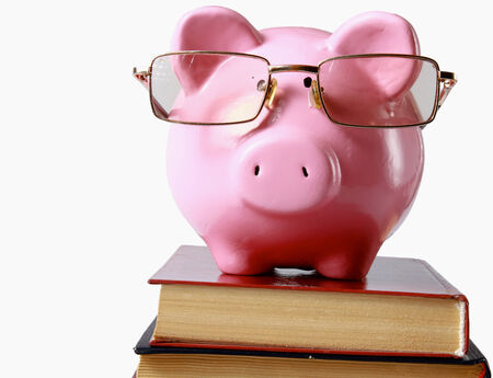 piggy bank with glasses and bookin isolated white background.の写真素材
