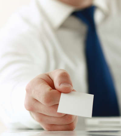 Portrait of young handsome business man holding blank white business card.の写真素材