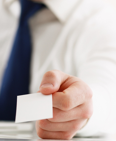 Portrait of young handsome business man holding blank white business cardの写真素材