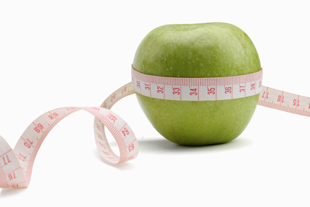 A green apple and a measuring tape isolated on white backgroundの写真素材