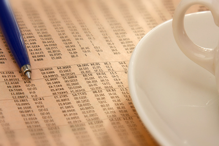 Closeup of a cup of coffee and a pen on a morning newspaperの写真素材