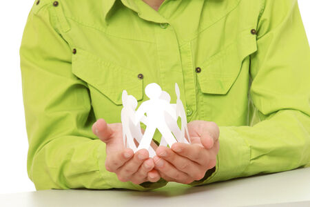 A young guy sitting at the desk, making paper people, focus on his handsの写真素材