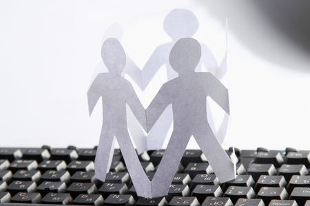 A circle of paper cutted people on a keyboardの写真素材