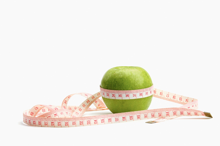 A green apple and a measuring tapeの写真素材