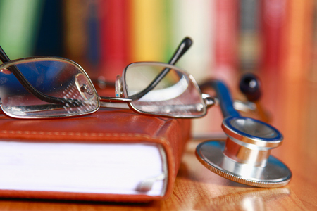Close-up of a notebook, spectacles, stethoscope on the deskの写真素材