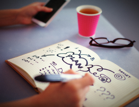 Young woman writes to diary on a white tableの写真素材