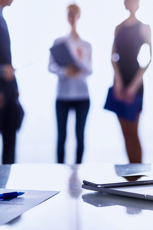 Laptop  computer on  desk ,  businesspeople standing in the backgroundの写真素材