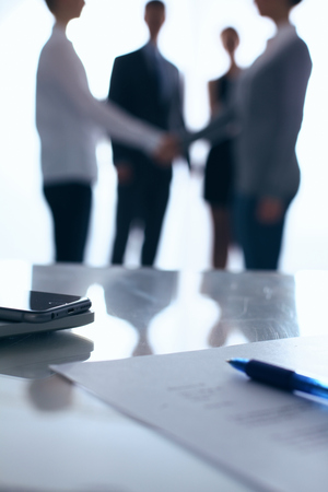 Laptop  computer on  desk ,  businesspeople standing in the backgroundの写真素材
