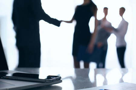 Laptop  computer on  desk ,  businesspeople standing in the backgroundの写真素材