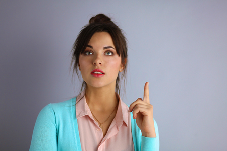 Portrait of an attractive fashionable young brunette woman pointing upの写真素材