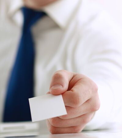 Portrait of young handsome business man holding blank white business cardの写真素材