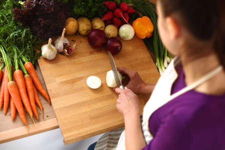 Young woman cutting vegetables in the kitchen .の写真素材
