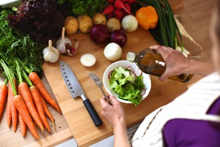 Young woman cutting vegetables in the kitchen .の写真素材