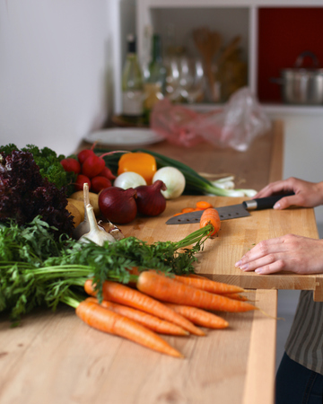 Pair of young woman\'s hand cutting vegetables in the kitchen .の写真素材