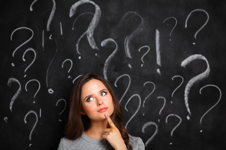 Young girl with question mark on a gray background .