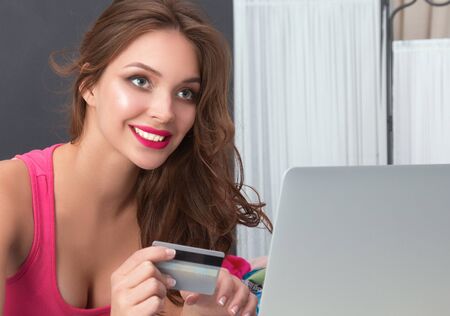 Happy woman lying bed surrounded by her clothes .の写真素材