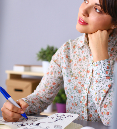 Young woman writes to diary on a white table .の写真素材